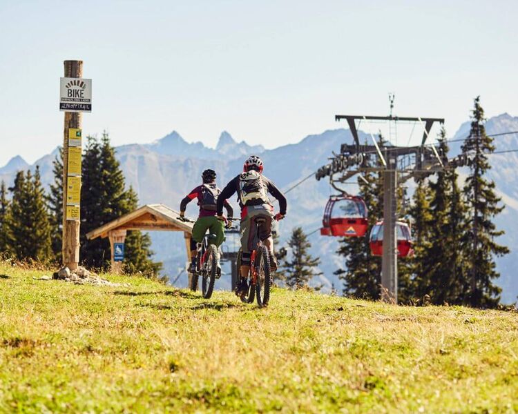 Mountainbiker fahren am Biketrail unterhalb einer Sommerbergbahn in Serfaus-Fiss-Ladis
