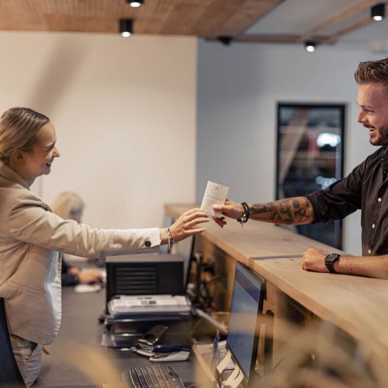 A receptionist hands her guest a key card.