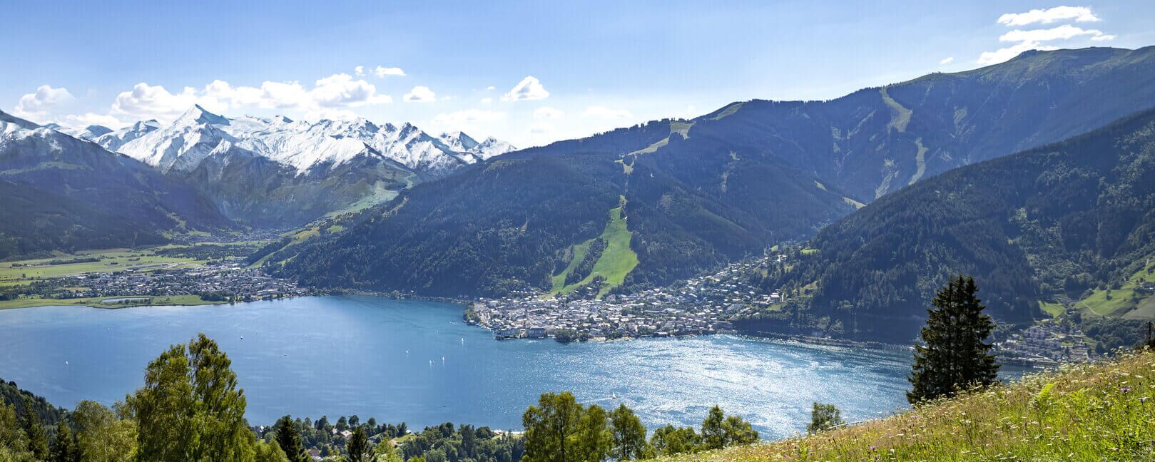 Lake Zell nestled between mountains, the Kitzsteinhorn glacier, blooming meadows, and the town of Zell am See.