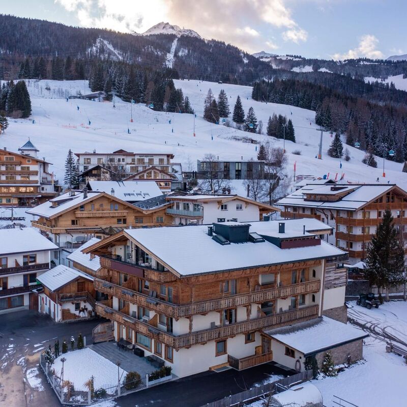 Aerial view of charming snow covered holiday apartments with the ski slope in the background.