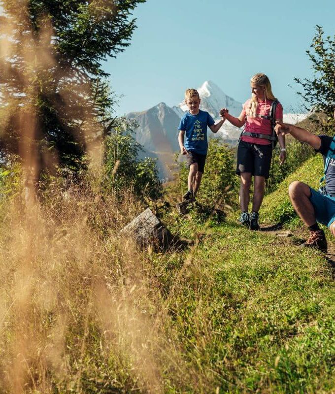 Familie mit 2 Kindern bei einer kurzen Rast am Maiskogel, im Hintergrund das Kitzsteinhorn.