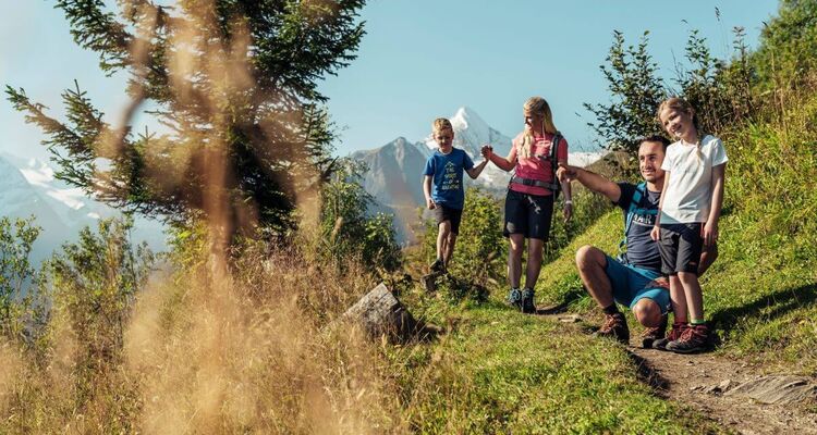 A family with two children takes a short break on the Maiskogel, with the Kitzsteinhorn in the background.