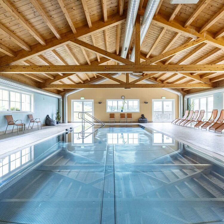 Ruim overdekt zwembad in het resort met zwembad, houten plafond, panoramische ramen en ligstoelen voor ontspannen uren