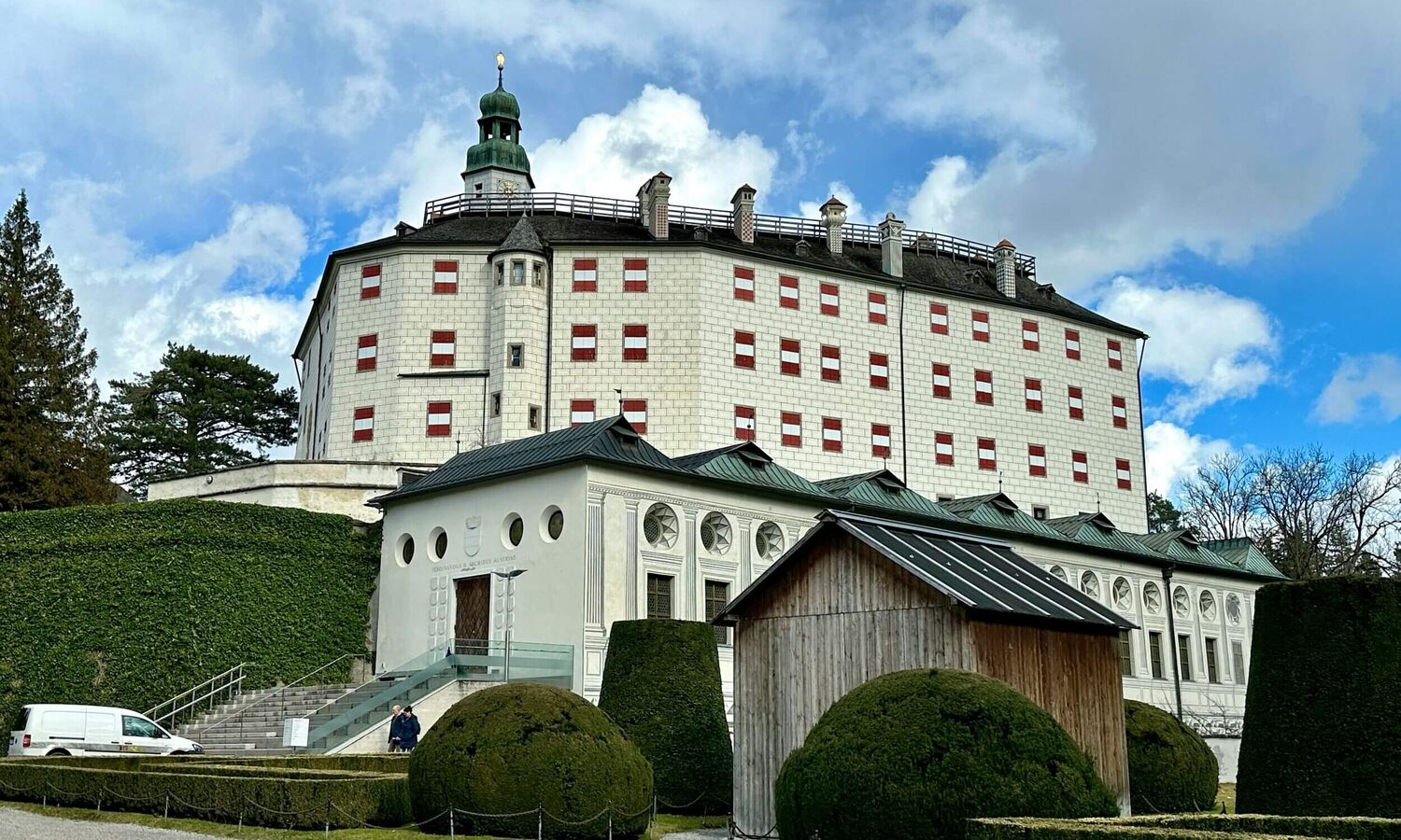 Ambras Castle with red-white-red shutters, surrounded by manicured gardens
