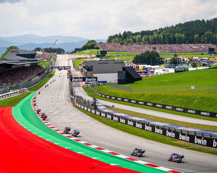 Motorräder fahren auf der Rennstrecke beim MotoGP-Rennen in Österreich, Zuschauer genießen das Event. | © Name