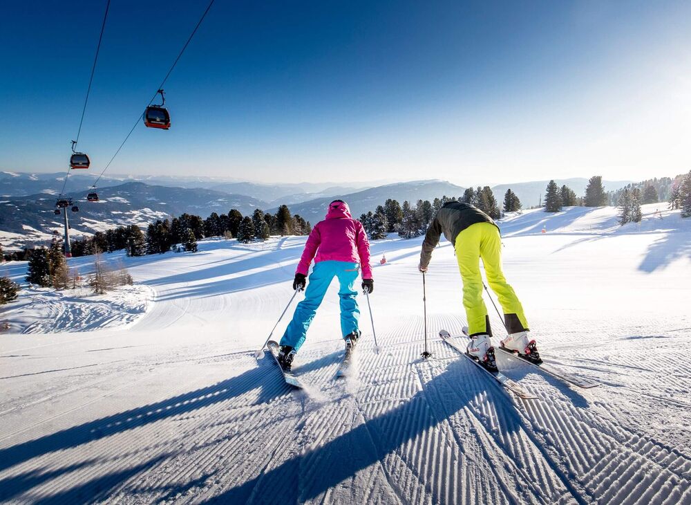 Auf einer sonnigen, bestens präparierten Piste am Kreischberg starten zwei Skifahrer ein Wettrennen.