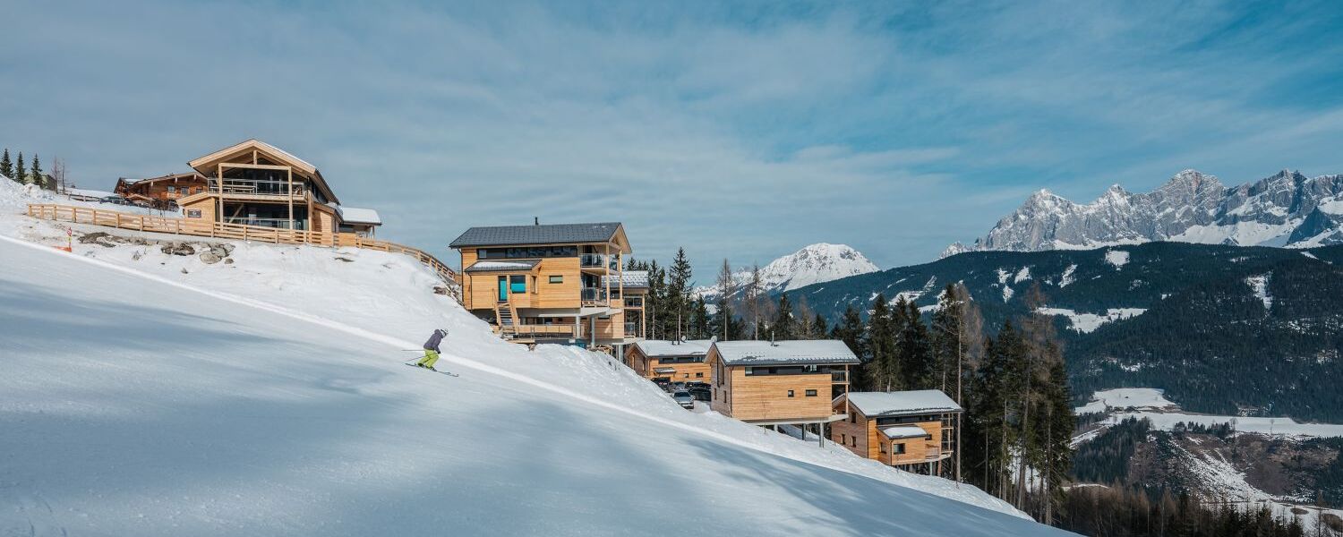 Skipiste mit Skifahrer vor Ferienhaus auf der Reiteralm in Schladming