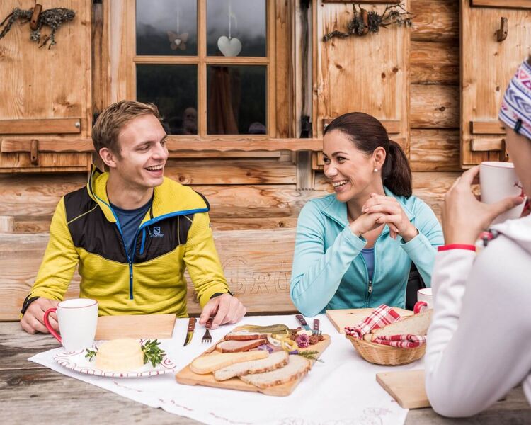 Traditionelle Jause auf einer Alm mit regionalen Spezialitäten in alpiner Berglandschaft