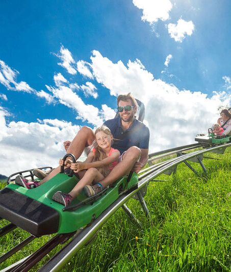 Familie saust in 2 Wagen den Alpine Coaster Maisiflitzer hinunter.