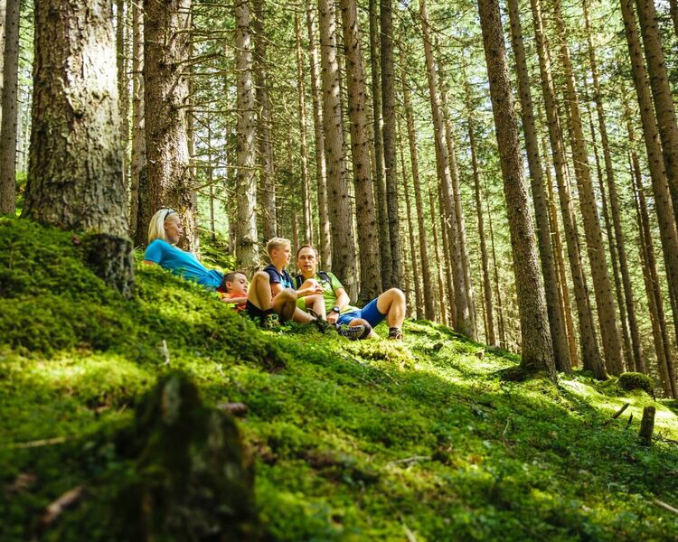Parents resting with their 2 children on the mossy forest floor © TVB Rauris