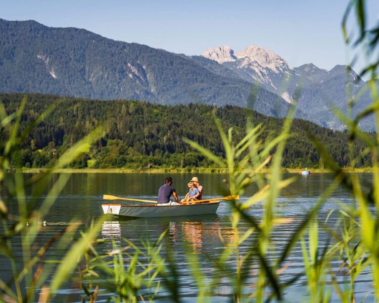 Menschen beim Baden am Pressegger See mit klarem Wasser, Badesteg und sommerlicher Bergkulisse.