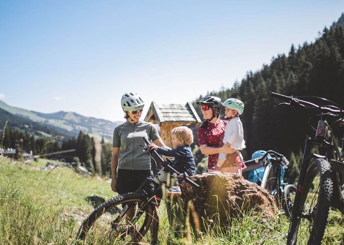 Familie beim Mountainbiken in der Berglandschaft von Saalbach.