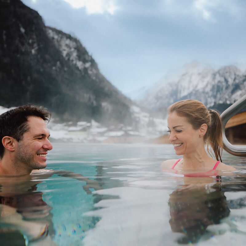 Pärchen entspannt im Infinity Pool mit Blick auf das Kitzsteinhorn