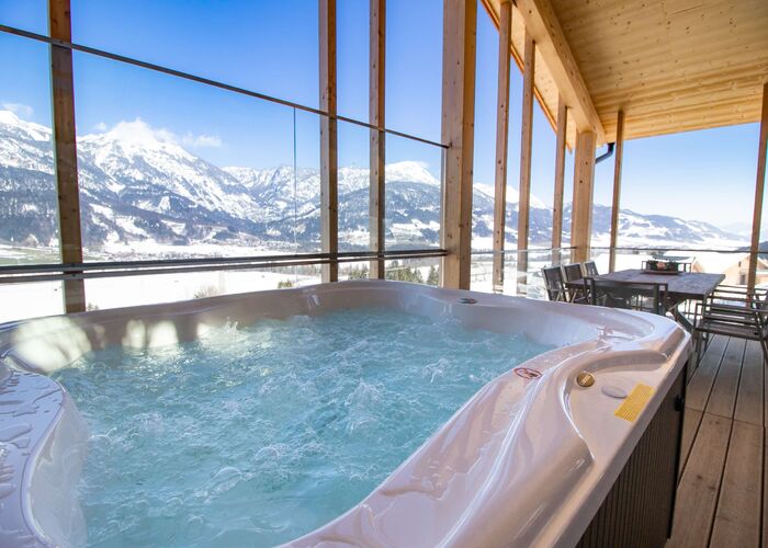 Gemütlicher Whirlpool/Jacuzzi auf der überdachten Terrasse mit Ausblick auf eine winterliche Bergwelt