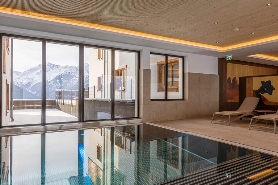 Indoor pool with cozy chair and unique view to the Tauern