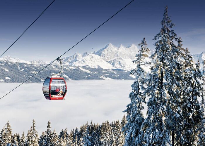 Rote Kabinenbahn über dem Nebelmeer mit Bergpanorama