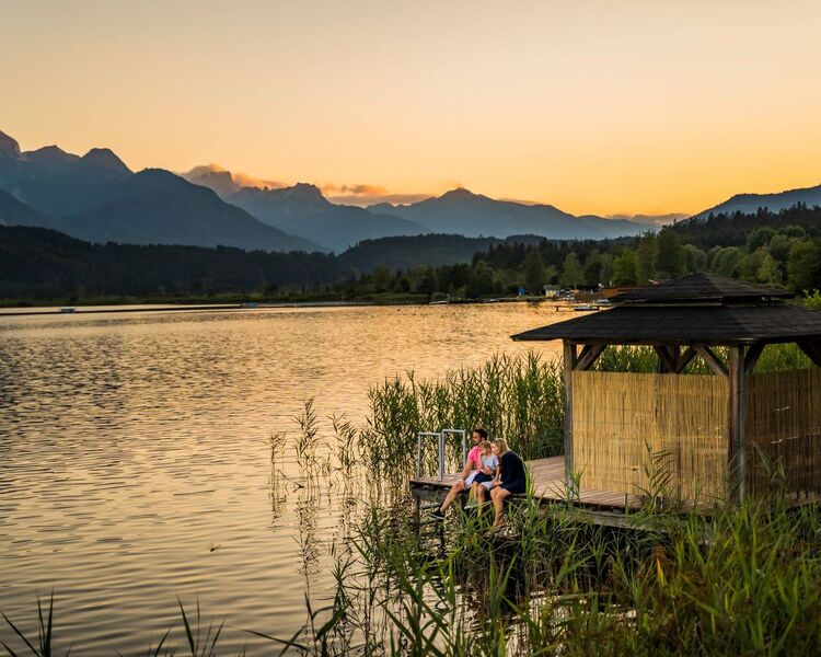 Blick auf den Pressegger See in Kärnten mit ruhigem Wasser, Naturufer und alpiner Landschaft.