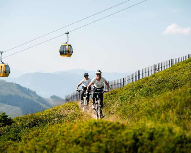 Mountain biker with a mountain panorama and cable car in Saalbach