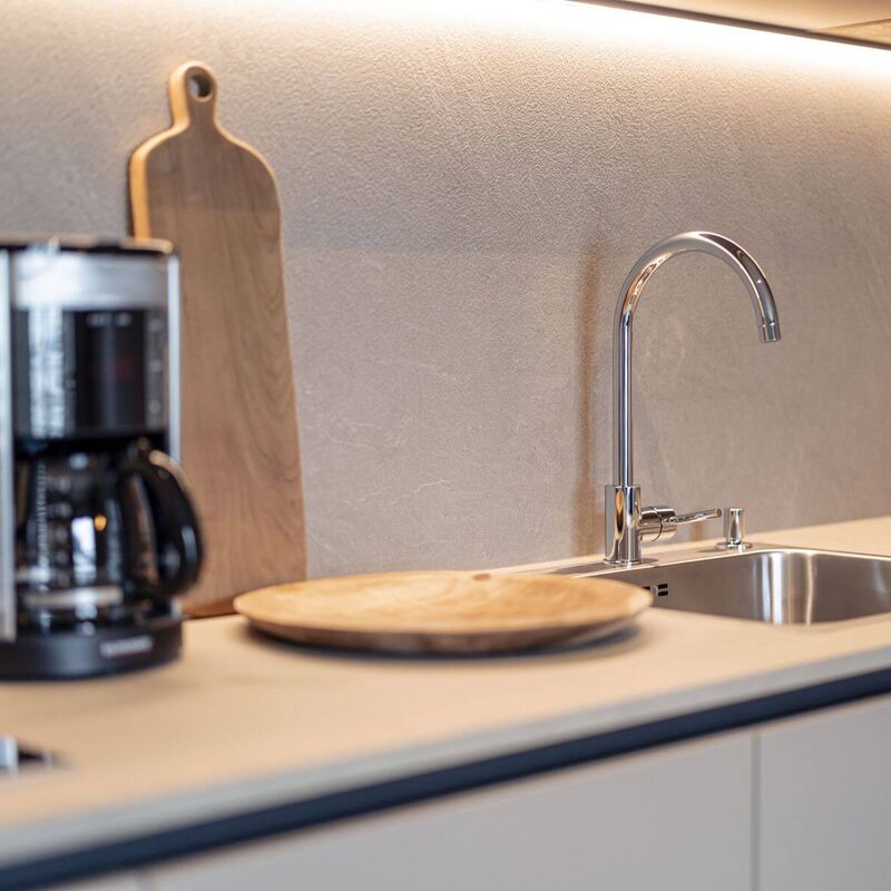 Beige, moderne Küchenzeile mit Spülbecken, Filterkaffeemaschine und Holzschneidebrett