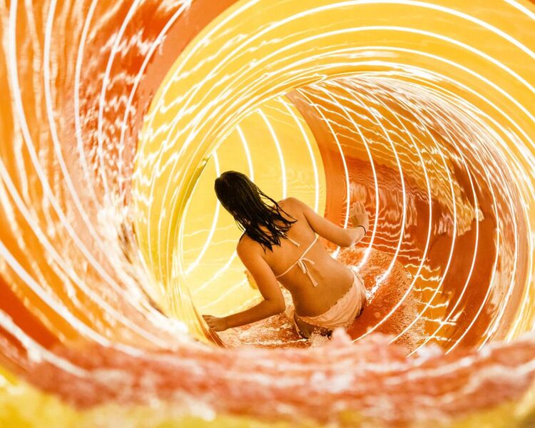 Girl in an orange-yellow tube slide at an adventure thermal spa