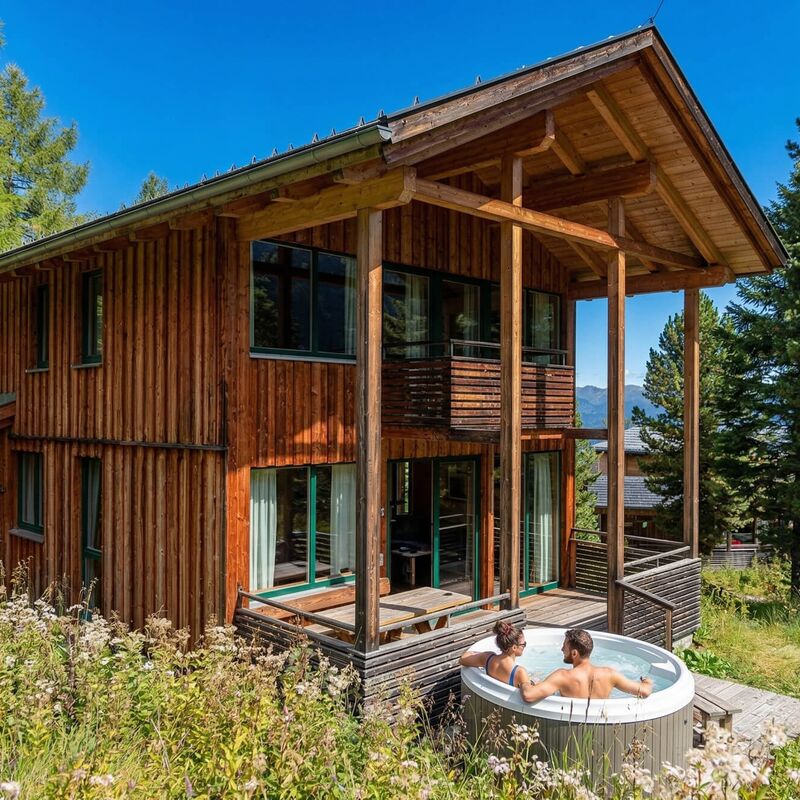 Pärchen entspannt im privaten Whirlpool vor dem Chalet mitten im Wald.