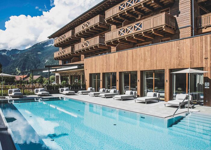 Eleganter Poolbereich mit bequemen Liegen und Blick auf die Berge lädt zum Entspannen ein.