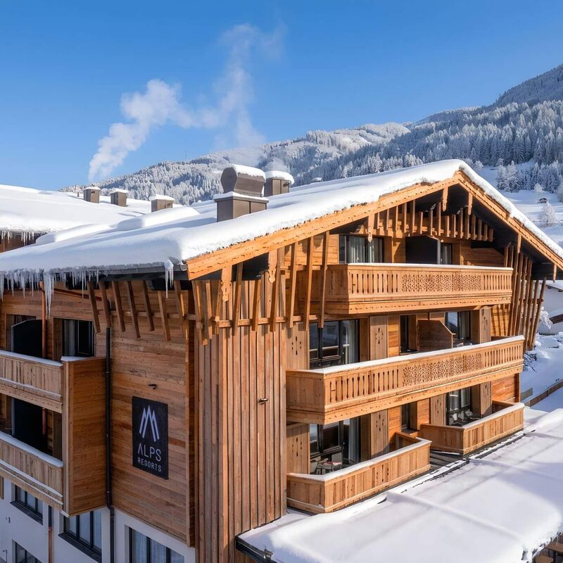 Außenansicht des Carpe Solem Kaprun im Winter, umgeben von verschneiter Landschaft und der winterlichen Bergwelt von Kaprun.