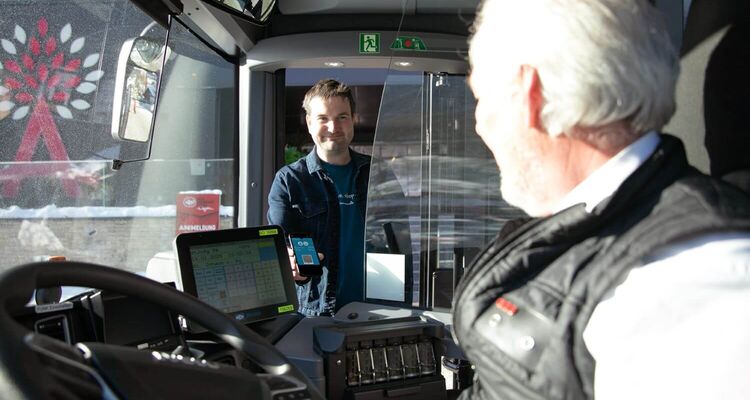 Een man begroet de buschauffeur als hij in de bus stapt en toont zijn mobiliteitsticket voor gasten.
