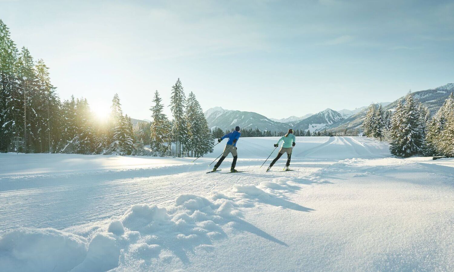 Two cross-country skiers on a perfectly groomed trail in a fairytale winter landscape