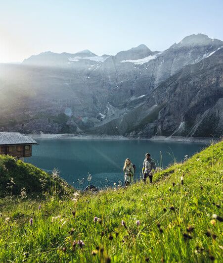 Wanderer am oberen Kapruner Hochgebirgsstausee vor hochalpinem Gelände.