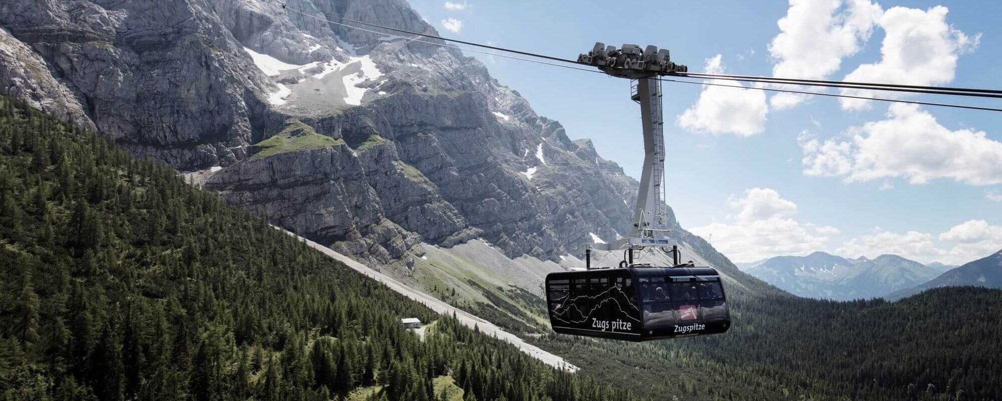A modern verglaste Panoramagondel of the Zugspitz Pendelbahn ascends towards Zugspitze's stunning peaks.