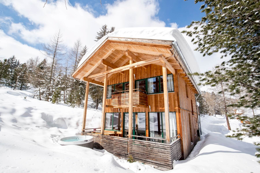 Holiday home in a snow covered forest landscape and hot tub