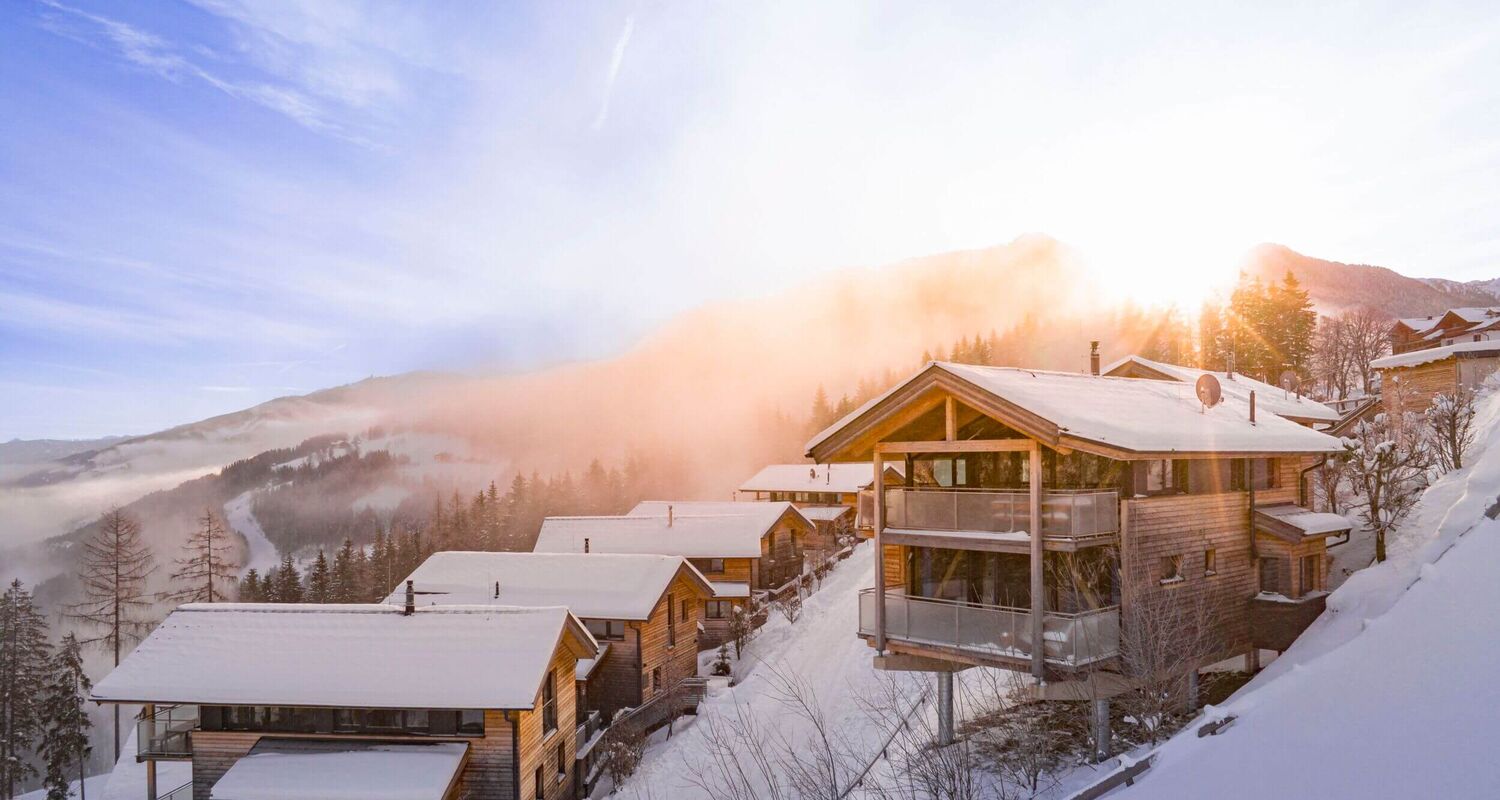 Holiday homes and chalets in a snowy winter landscape and sunrise