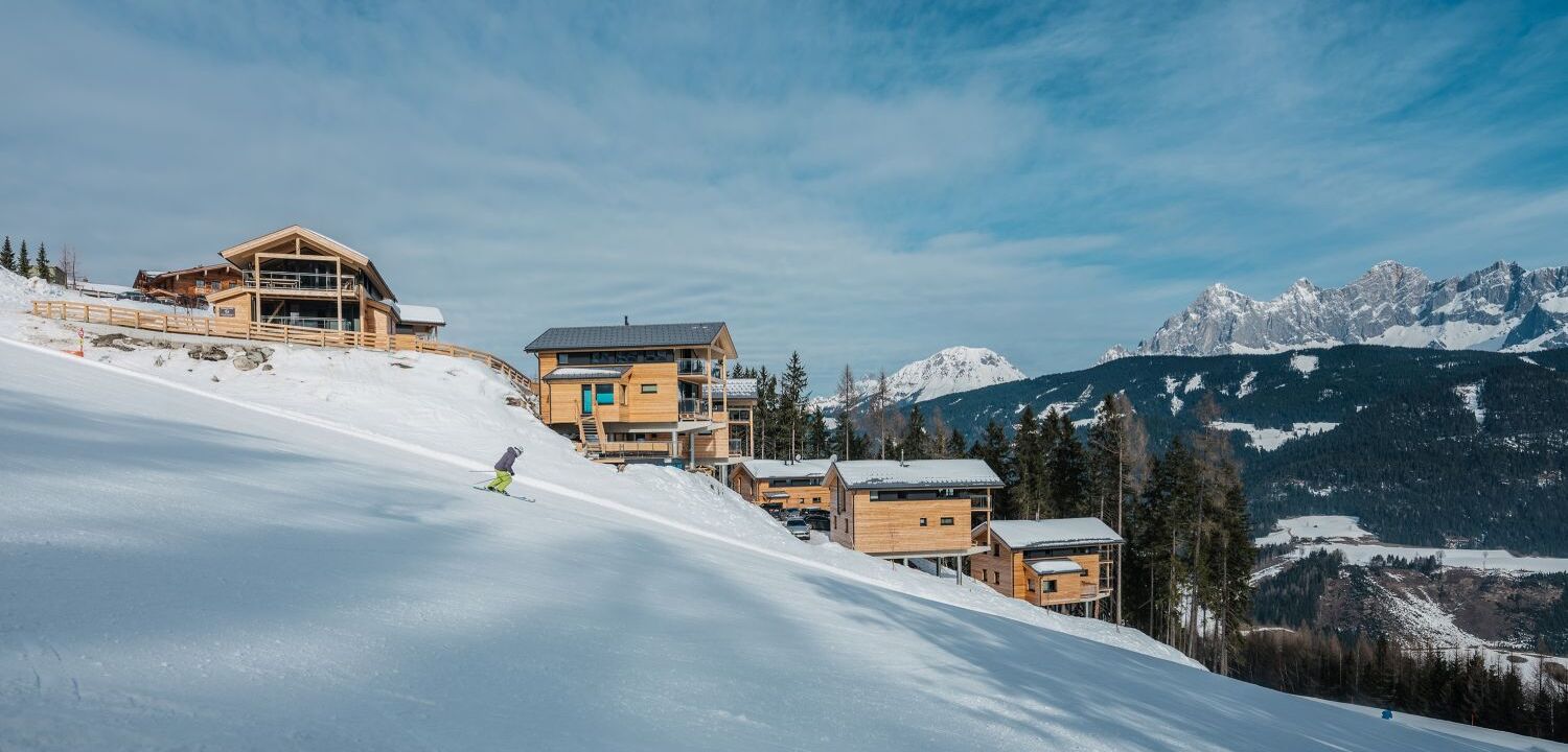 Skipiste in Schladming mit Ferienhäusern im Hintergrund