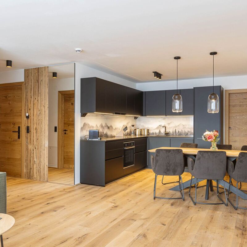 Open plan kitchenette with dining table and living area at Fiss Suites