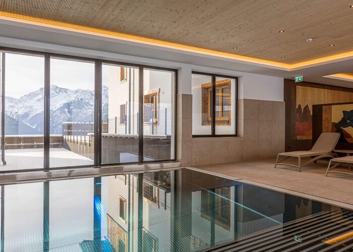 Indoor pool with cozy chair and unique view to the Tauern