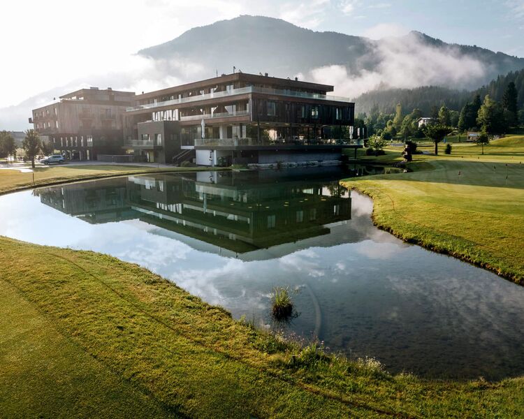 Das Berg & Golf Resort Westendorf spiegelt sich im Teich und bietet eine idyllische Umgebung in den Alpen.