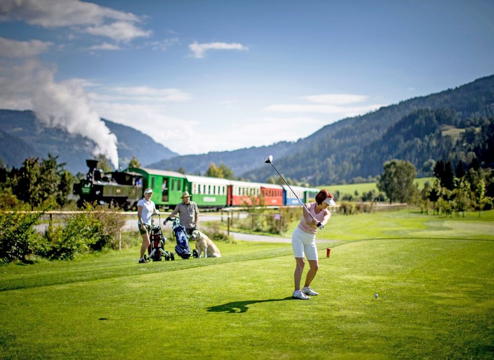 Golfer on the golf course, the Murtalbahn in the background