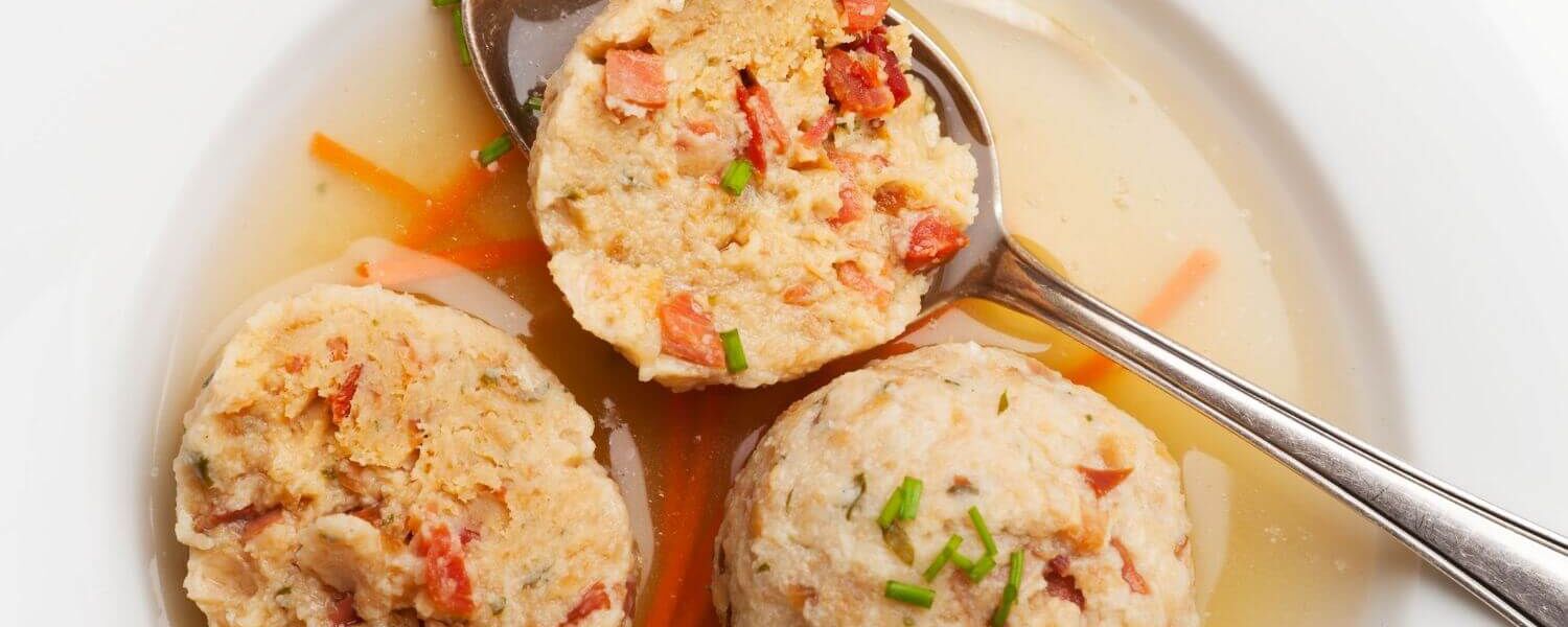Leckere Speckknödel in Brühe, perfekt für Meal Prep in der Ferienwohnung, um stressfrei im Urlaub zu genießen.