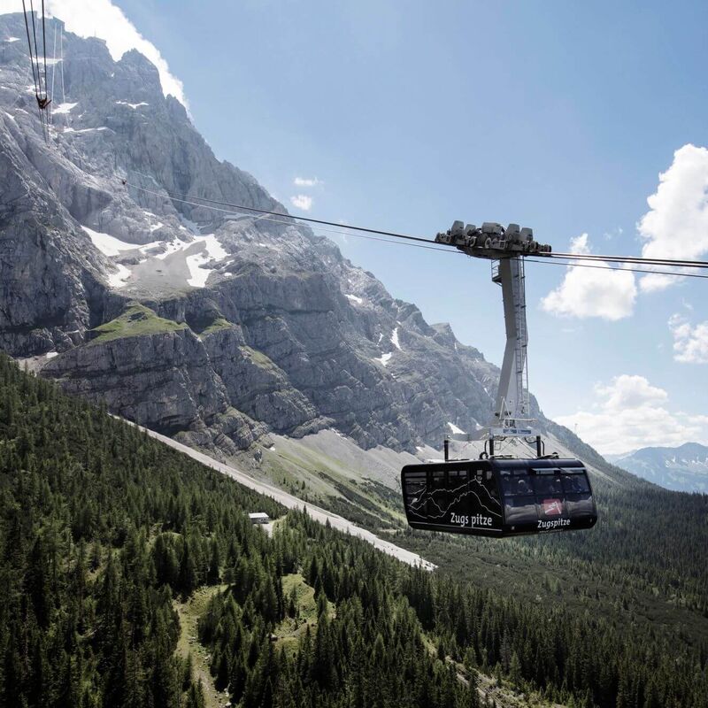 A modern verglaste Panoramagondel of the Zugspitz-Pendelbahn ascends towards Zugspitze's stunning peaks.