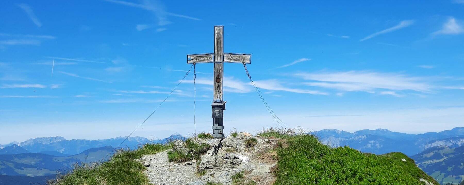 Gipfelkreuz am Brechhorn mit Blick auf die Tiroler Alpen
