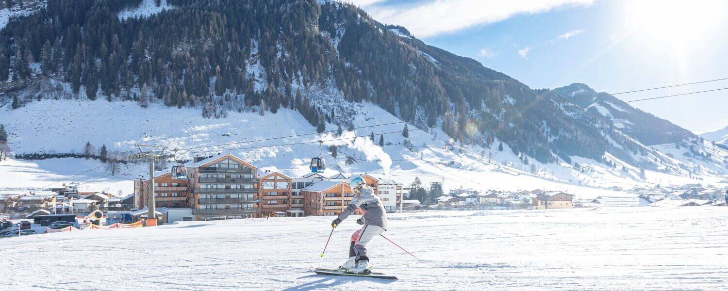 Skifahrer mit dem Apartmentresort Carpe Solem Rauris im Hintergrund