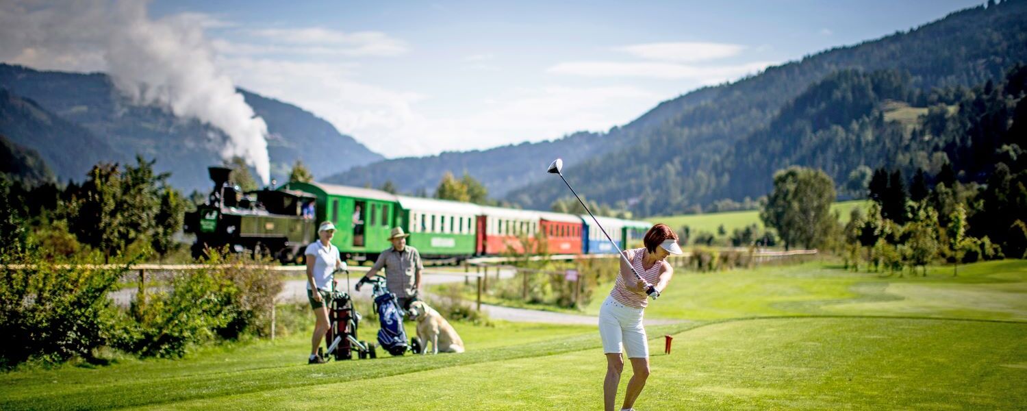 Golfer on the golf course, the Murtalbahn in the background