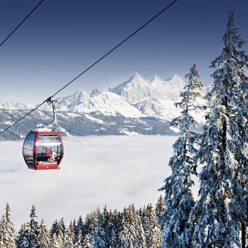 Rote Kabinenbahn über dem Nebelmeer mit Bergpanorama