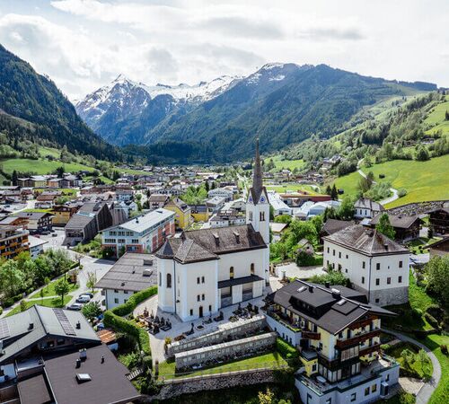 Blick von oben auf das Ortszentrum von Kaprun mit seiner Kirche, im Hintergrund das Kitzsteinhorn.