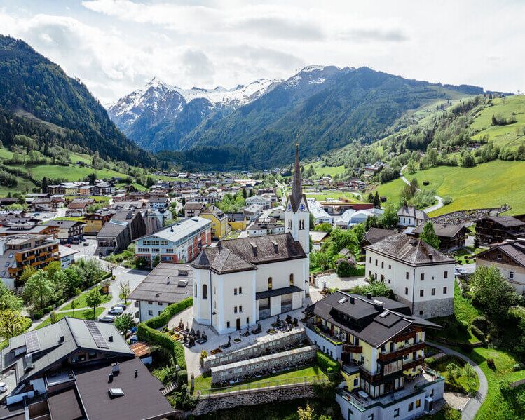 View from above of Kaprun’s village centre with its church, with the Kitzsteinhorn rising in the background.