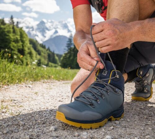 Ein Mann beim Binden seiner Salomon Bergschuhe