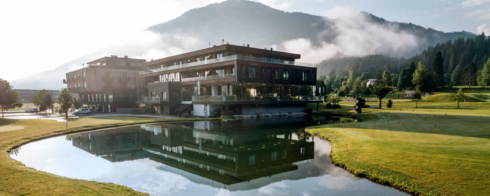 Das Berg & Golf Resort Westendorf spiegelt sich im Teich und bietet eine idyllische Umgebung in den Alpen.