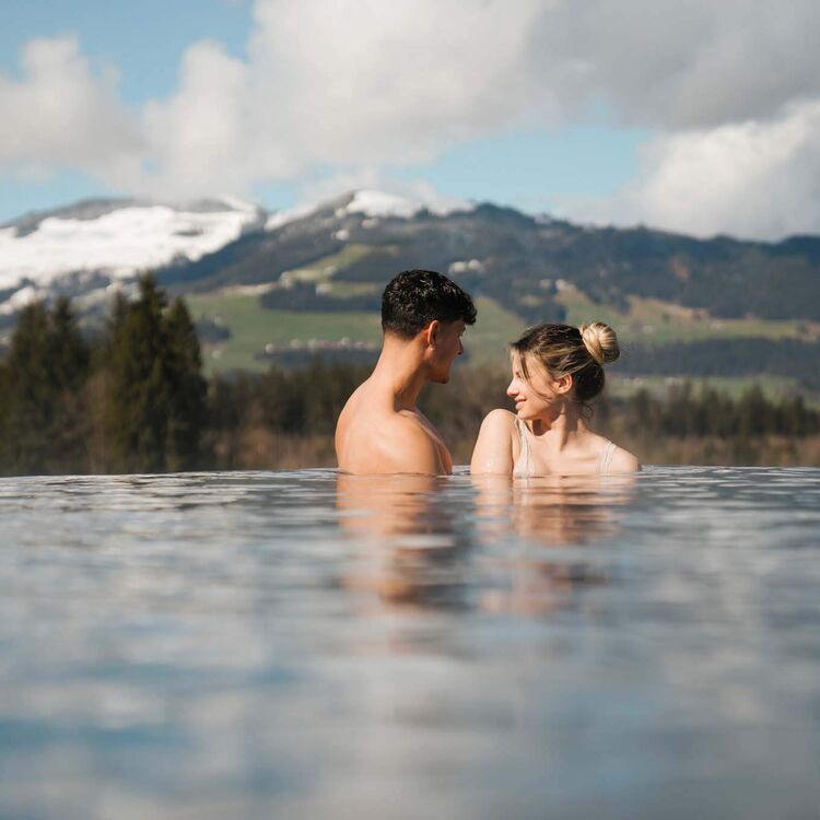 A couple enjoys a serene moment in an infinity pool overlooking the stunning Alps.