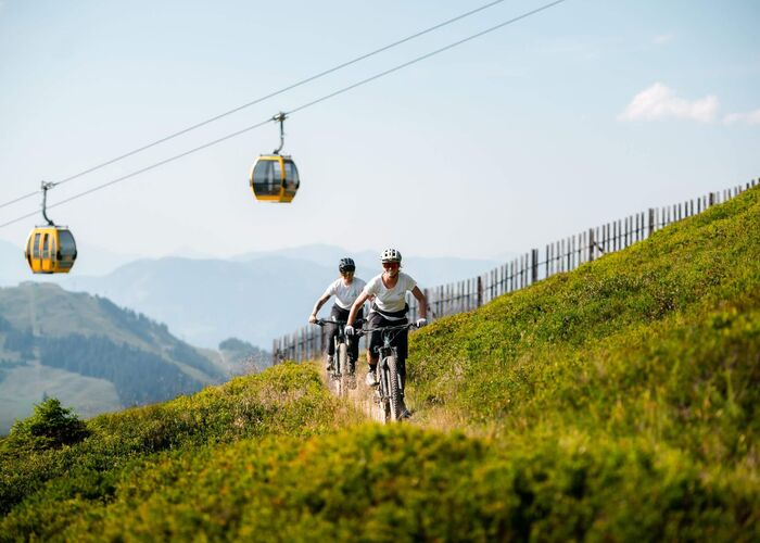 Mountainbiker mit Bergpanorama und Bergbahn in Saalbach.